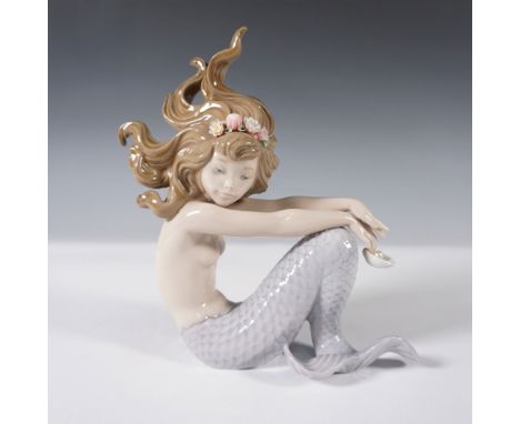This enchanting mermaid is depicted in a seated position, gracefully holding a delicate shell containing a pearlescent pearl.
