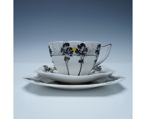 Three-piece tea set made of fine porcelain, decorated with a stylized landscape design featuring black trees and a yellow sun