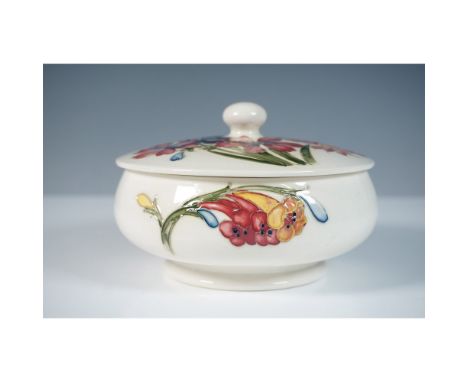 A Moorcroft pottery powder bowl, designed by William Moorcroft, featuring the delicate Spring Flowers pattern. This lidded bo