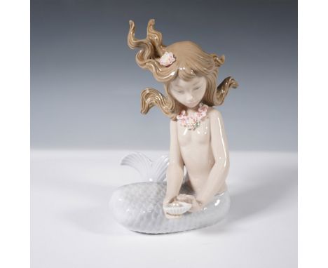 This exquisite porcelain figurine from Lladro captures the ethereal beauty of a mermaid with flowing hair adorned with delica