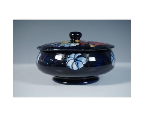 This Moorcroft pottery covered bowl showcases the brand's signature floral motifs, designed by William Moorcroft. The piece i