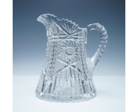 A striking cut glass water pitcher featuring an intricate geometric starburst and fan motif. The body of the pitcher showcase