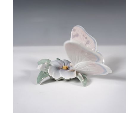 A finely crafted Lladro porcelain figurine featuring a delicate butterfly resting on a flower. This piece showcases soft past