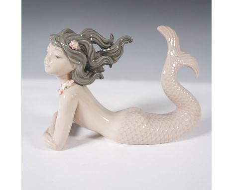 This Lladro porcelain figurine, Fantasy, captures the essence of a mystical mermaid as she gracefully rests with her tail arc