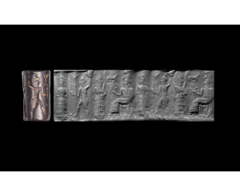 Late 3rd millennium BC.A haematite cylinder seal with intaglio frieze of a seated figure in flounced robe holding a sceptre c