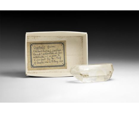 A prismatic quartz crystal in white card tray with old collector's label reading: 'Crystals from Escherhorn (Switzerland)coll