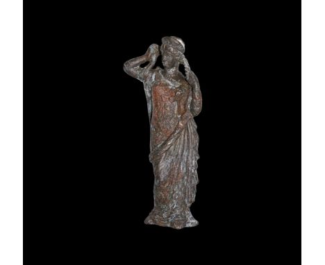 1st-2nd century AD.   A bronze statuette of Venus, standing, wearing loose robes falling to feet, mantle over left arm; steph