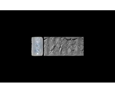 9th-8th century BC.   A chalcedony cylinder seal with frieze of a standing winged and robed figure gripping the fore-paws of 