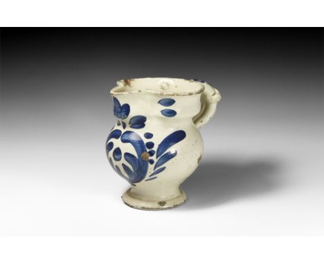Italian, 17th century AD.A ceramic jug with white slip and blue painted decoration to the front in the form of a stylised pla