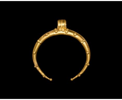 2nd-3rd century AD.   A tapering gold crescent pendant with granule detailing, ribbed suspension loop. Cf. Marshall, F.H. Cat
