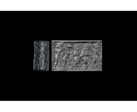 Late 3rd millennium BC.A black limestone cylinder seal with frieze of standing heroes grappling with rearing beasts with bear