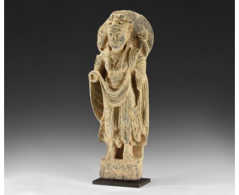 3rd-4th century AD.   A schist figure of the bodhisattva Maitreya standing, large halo behind head with plant motif to the ri