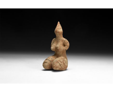 4th millennium BC.A ceramic figurine of a female with legs folded, arms supporting the breasts, conical head with pinched fac