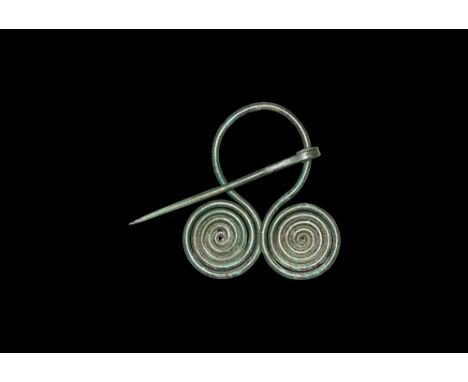 2nd millennium BC.   A penannular bronze brooch formed from a round-section rod with outward-coiled finials, hipped securing 