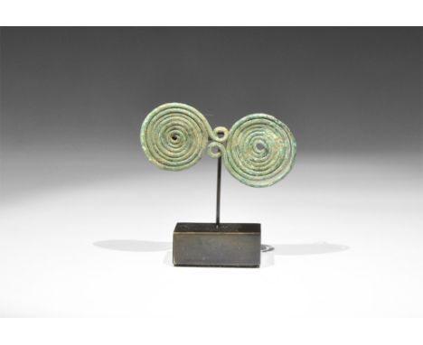 9th-7th century BC.A bronze spectacle brooch formed as two large tightly-wound coils with 8-shaped intermediate coils, remain