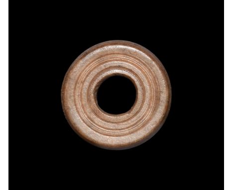 1st-2nd century AD.A turned bone spindle whorl with concentric rings, gussetted profile. See Allason-Jones, L. & Miket, R. Th