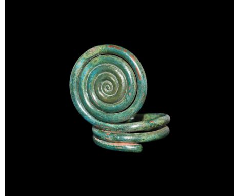 2nd millennium BC.A bronze ring with two-loop shank and perpendicular coiled plaque. See Richter, I. Der Arm- und Beinschmuck