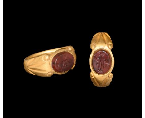 2nd-3rd century AD.   A gold ring with tapering flat section shank, flaring at the shoulder and widening to the bezel, engrav