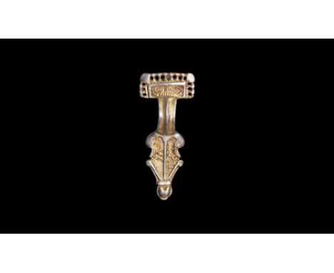6th century AD.A parcel-gilt silver bow brooch comprising a rectangular headplate with raised border and openwork band of pel