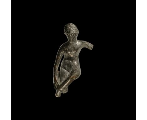 1st-2nd century AD.   A bronze figure of Venus (Aphrodite) seated nude with right hand extended to the left foot placed on th