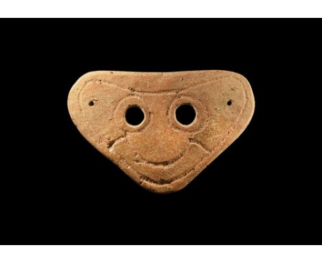 4th-3rd century BC.A small triangular-shaped slightly curved ceramic mask with two eye-holes and incised stylised facial deta