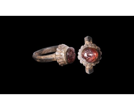 3rd-7th century AD.A keeled D-section silver hoop with rosette bezel, inset garnet cabochon with intaglio bird. 4.88 grams, 2