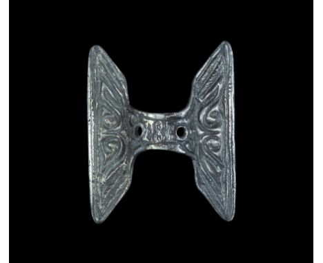 5th century AD.   A silver bow-brooch with identical trapezoidal head- and footplate; opposed spiral and billet decoration on