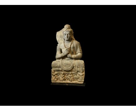 3rd-4th century AD.A schist figure of the bodhisattva Maitreya seated cross-legged, hair pulled up into a top knot and fallin