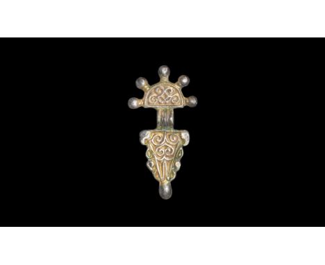 6th century AD.   A parcel-gilt silver bow brooch with D-shaped headplate and five radiating knops, spiral tendrils, shallow 