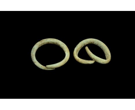 2nd millennium BC.   A pair of substantial bronze penannular bracelets, each a round-section bar with tapering ends; possibly