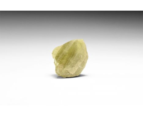 A large single crystal of yellow-green brazilianite in white card tray; with adhesive tape label reading: 'BRAZILIANITE'. 59.