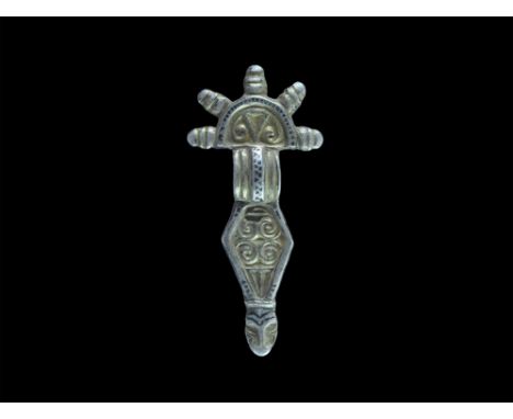 Late 5th-early 6th century AD. A silver parcel-gilt bow brooch comprising: a D-shaped headplate with chevron and scrolls, rai
