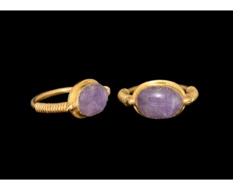 Late Period, 664-332 BC. An amethyst scarab with detailing to the head and wing case in a later gold ring of the stirrup type