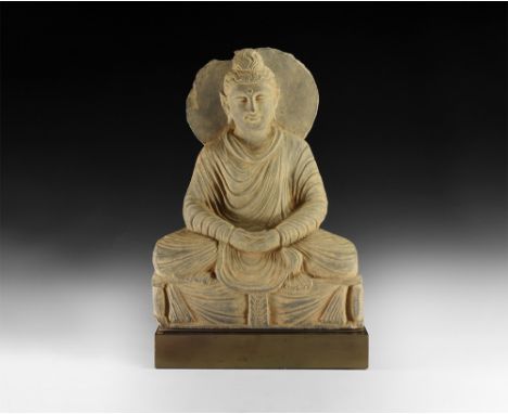 2nd century AD.A schist figure of the Buddha meditating, seated cross-legged in long robes, hands resting in lap; hair pulled