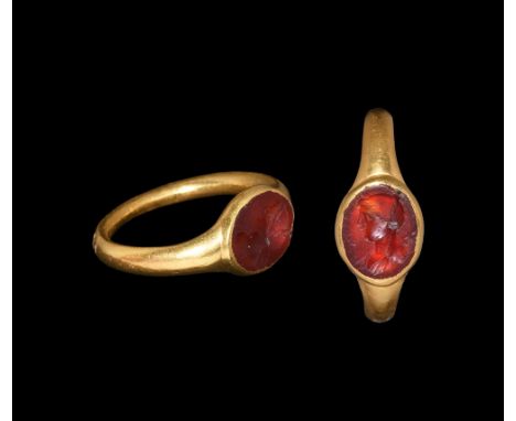 1st century AD.   A round-section gold hoop supporting a discoid bezel with inset carnelian intaglio female profile bust. Cf.