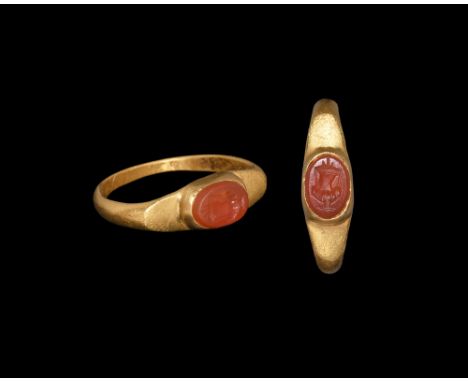 Later 2nd century AD.A D-section gold hoop with flared shoulders, flat elliptical plaque with central cell, inset carnelian c