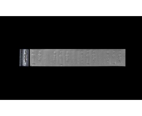 19th-16th century BC.A haematite cylinder seal engraved with a standing naked female facing frontally, a male worshipper wear