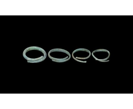 8th-4th century BC.   A group of four bronze open ended D-section torc bracelets with wide bodies to the centre, tapering to 