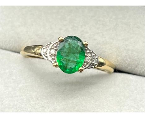 10ct yellow gold ring set with an oval cut emerald gem stone and diamond shoulders. [Ring size P] [2.29Grams] 