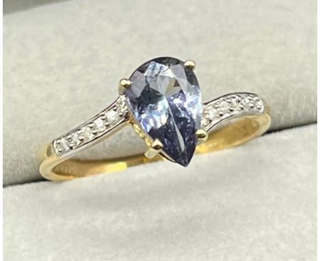 10ct yellow gold ring set with a pear drop cut blue Iolite gem stone off set by round cut white topaz stones to the shoulders