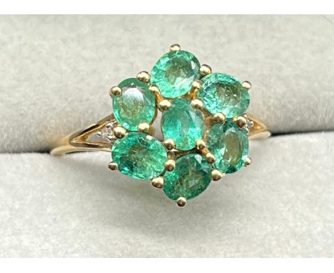 10ct yellow gold ring set with a cluster of seven oval cut emerald gem stones, with a single round cut diamond to each should