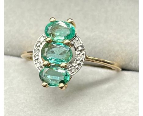 10ct yellow gold ring set with three oval cut emerald gem stones surrounded by diamonds. [Ring size Q] [2.04Grams] 