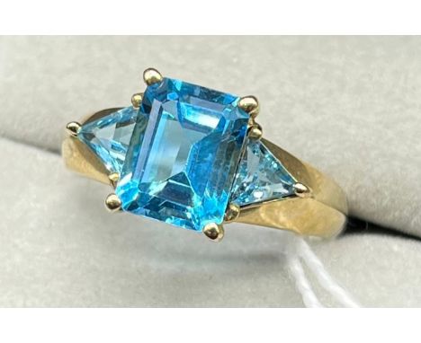 9ct yellow gold ring set with a Emerald cut blue topaz and two triangle cut blue topaz stones. [Ring size O] [3.29Grams] 