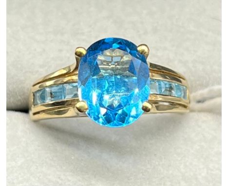 9ct yellow gold ring set with an oval cut blue topaz and emerald cut blue topaz gem stones. [Ring size N] [2.99Grams] 