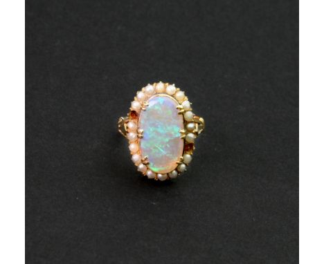 An opal and seed-pearl dress ring, claw-set with the oval opal at the centre within a surround of twenty seed pearls (two fur