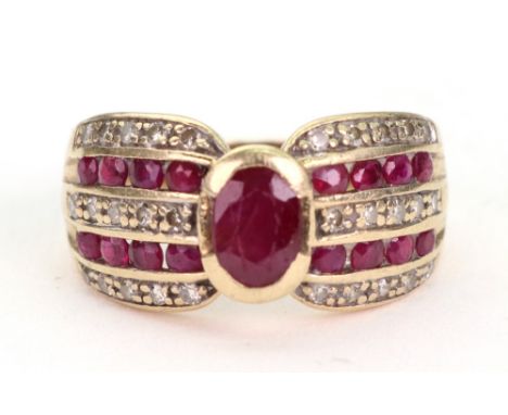 A 9ct yellow gold, ruby and diamond ring, centred by an oval mixed-cut collet set ruby between five bands of alternating diam