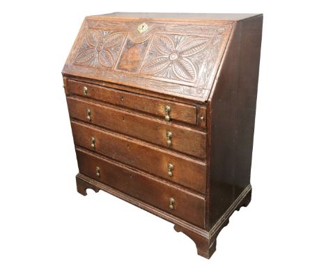 A mid 18th century oak bureau, the hinged fall later foliate carved and enclosing a fitted interior, four long drawers below,