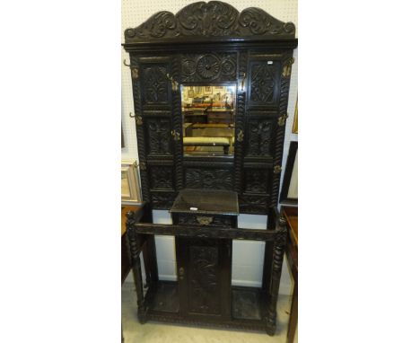 A Victorian Gothic Revival carved oak hall stand with coat hooks and stick stand flanking drawer and cupboard door