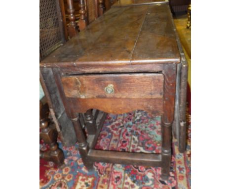 An 18th Century oak double gate-leg drop-leaf dining table with shaped apron and single end drawer, raised on turned and ring