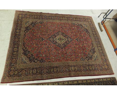 A Kashan carpet, the central floral decorated medallion on pale blue, cream and dark blue, on a pale red floral decorated gro